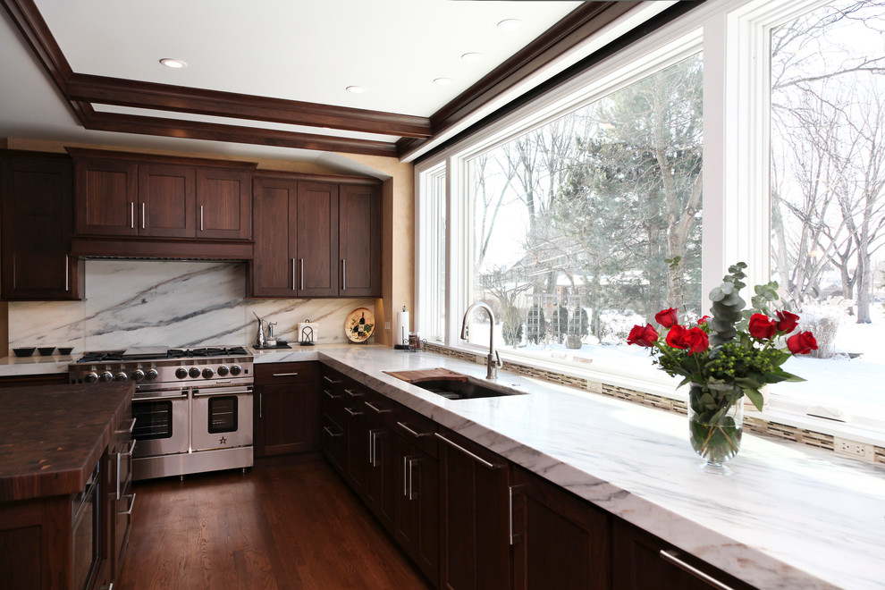 Exempel på ett mycket stort kök, med en undermonterad diskho, luckor med infälld panel, skåp i mörkt trä, marmorbänkskiva, vitt stänkskydd, stänkskydd i stickkakel, rostfria vitvaror, mellanmörkt trägolv och en köksö