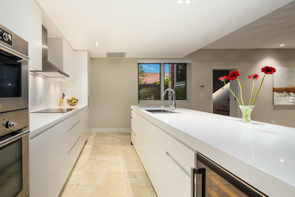 Foto på ett stort funkis linjärt kök och matrum, med en undermonterad diskho, vita skåp, granitbänkskiva, vitt stänkskydd, stänkskydd i sten, rostfria vitvaror, marmorgolv och en köksö