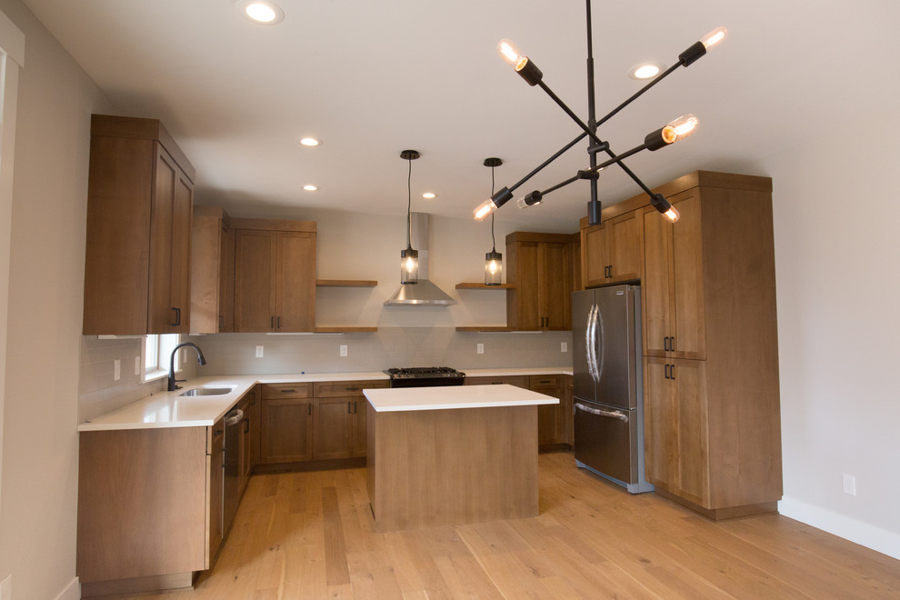 Eat-in kitchen - mid-sized craftsman u-shaped light wood floor and brown floor eat-in kitchen idea in Portland with an undermount sink, recessed-panel cabinets, medium tone wood cabinets, gray backsplash, ceramic backsplash, stainless steel appliances, an island and white countertops