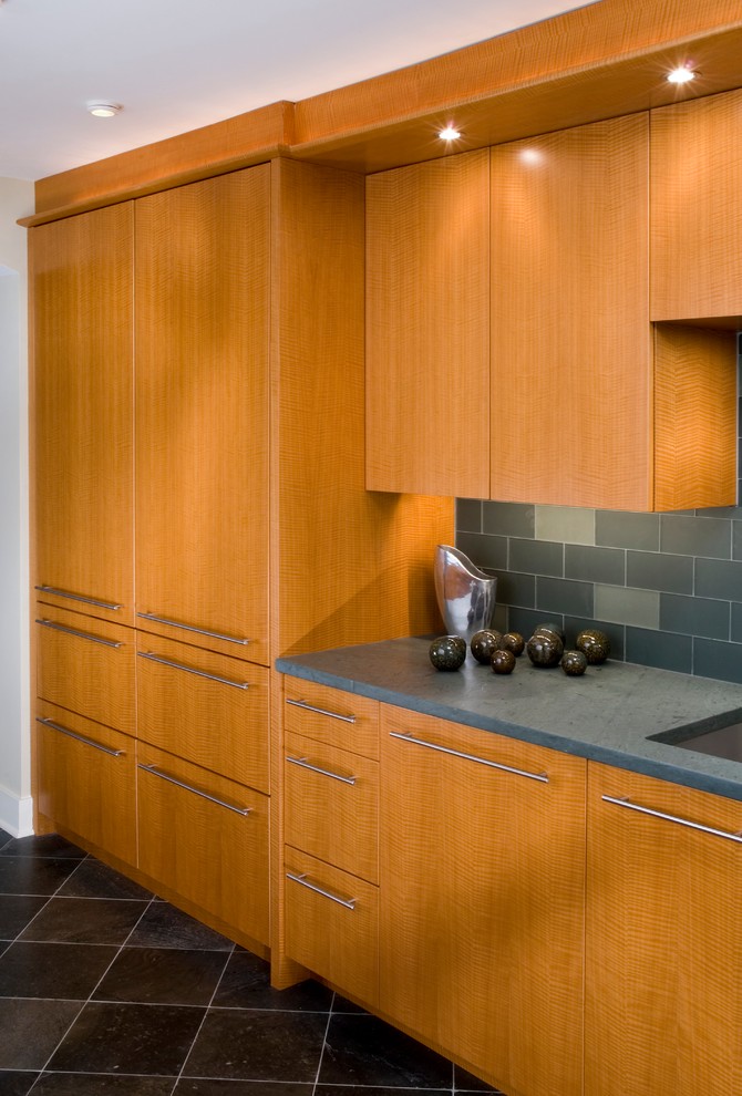 Modern inredning av ett stort kök, med en undermonterad diskho, släta luckor, skåp i ljust trä, blått stänkskydd, rostfria vitvaror, marmorgolv, en köksö, stänkskydd i tunnelbanekakel och svart golv