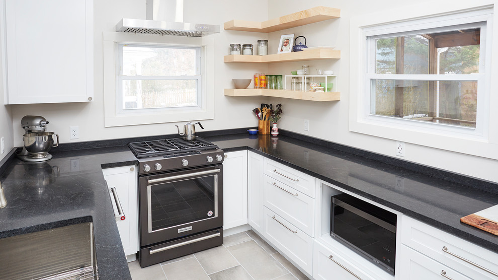 Exempel på ett mellanstort klassiskt svart svart kök, med en undermonterad diskho, skåp i shakerstil, vita skåp, granitbänkskiva, vitt stänkskydd, fönster som stänkskydd, rostfria vitvaror, klinkergolv i keramik, en halv köksö och grått golv