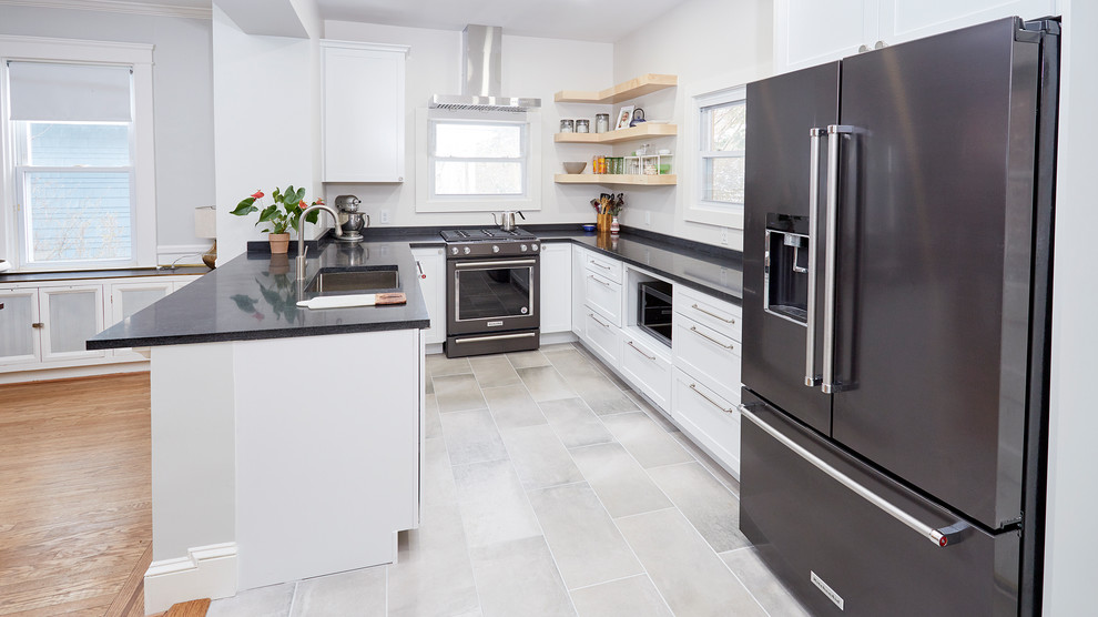 This is an example of a medium sized classic u-shaped kitchen/diner in Baltimore with a submerged sink, shaker cabinets, white cabinets, granite worktops, white splashback, window splashback, stainless steel appliances, ceramic flooring, a breakfast bar, grey floors and black worktops.