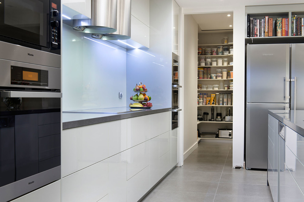 Zweizeilige Moderne Küche mit Unterbauwaschbecken, flächenbündigen Schrankfronten, grauen Schränken, Quarzwerkstein-Arbeitsplatte, Glasrückwand, Küchengeräten aus Edelstahl, Porzellan-Bodenfliesen und Kücheninsel in Melbourne
