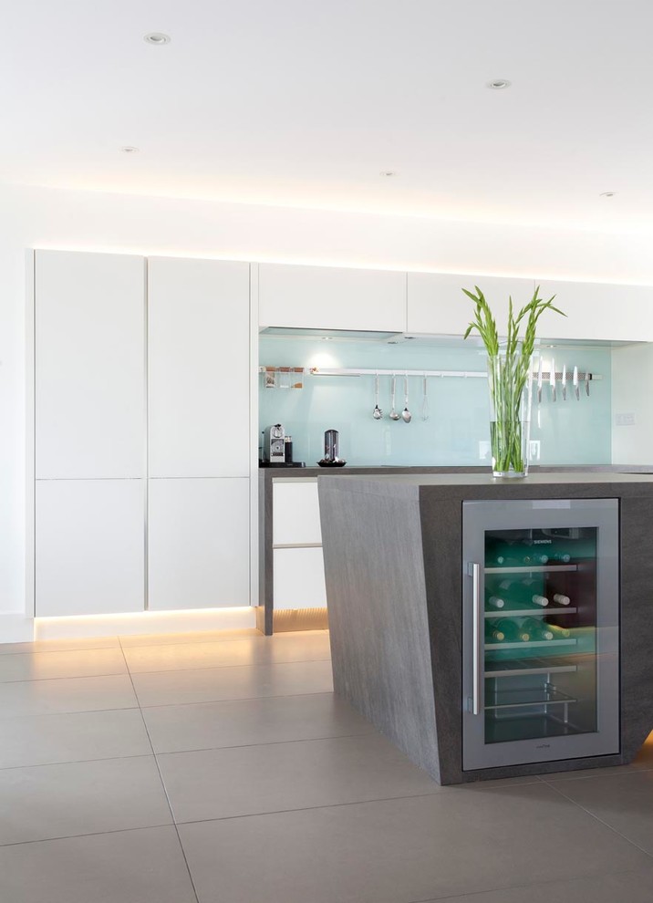Design ideas for an expansive contemporary u-shaped open plan kitchen in Other with an integrated sink, flat-panel cabinets, white cabinets, engineered stone countertops, green splashback, glass sheet splashback, stainless steel appliances, ceramic flooring and an island.