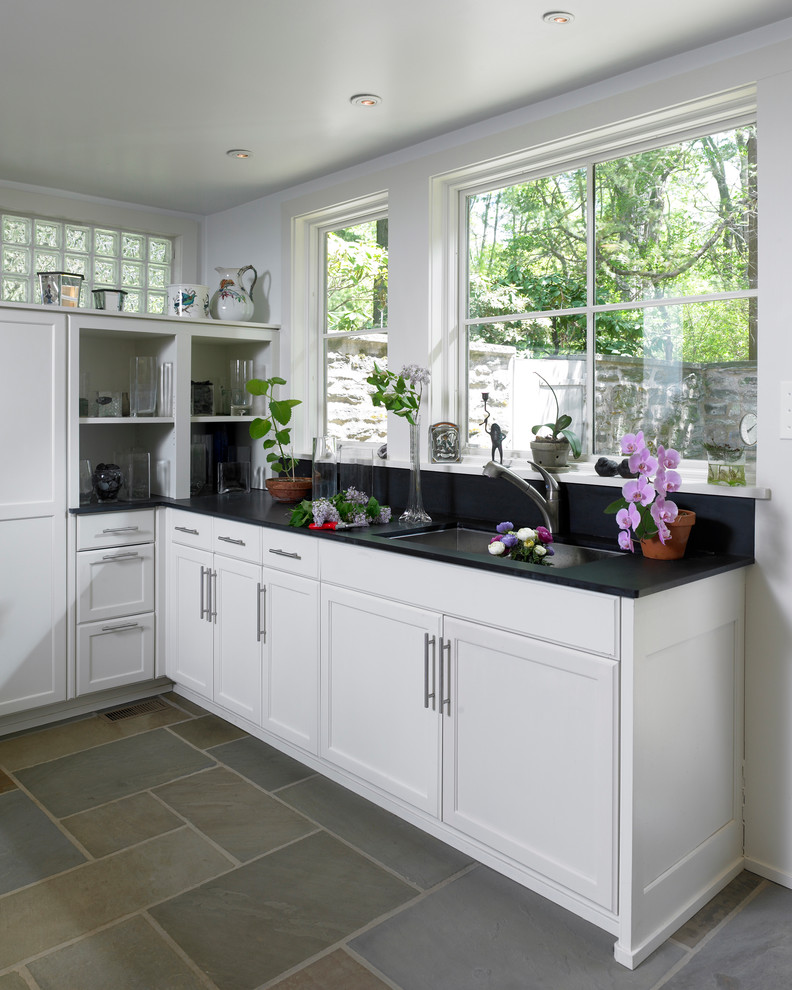 Immagine di una cucina minimal di medie dimensioni con lavello sottopiano, ante con riquadro incassato, ante bianche, paraspruzzi blu, paraspruzzi in lastra di pietra, elettrodomestici neri e pavimento in ardesia