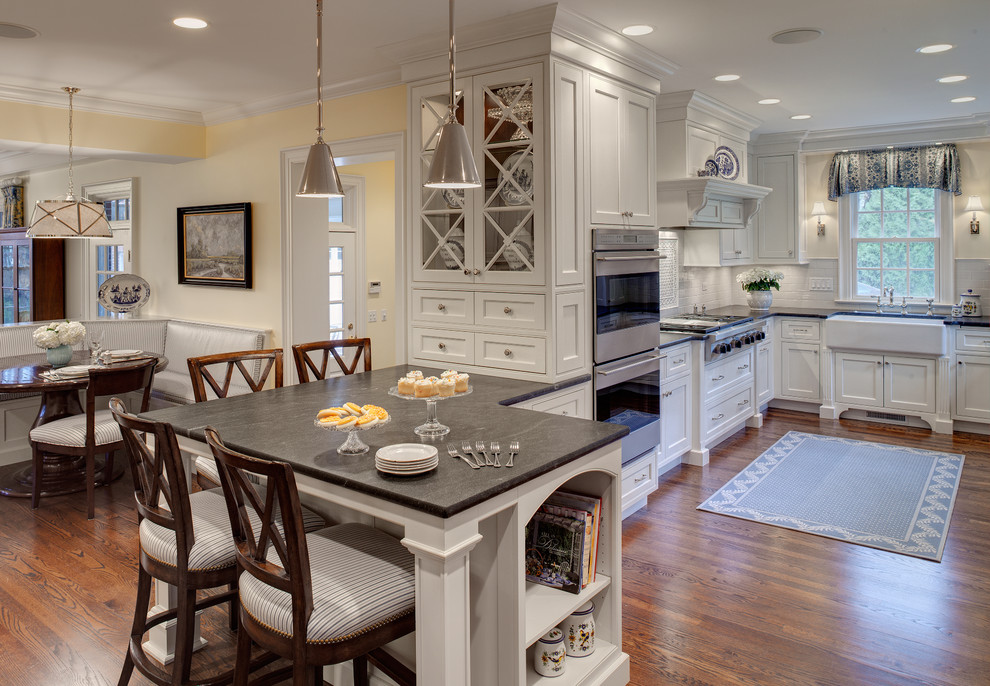 Example of a classic kitchen design in Chicago with a farmhouse sink, white cabinets and soapstone countertops