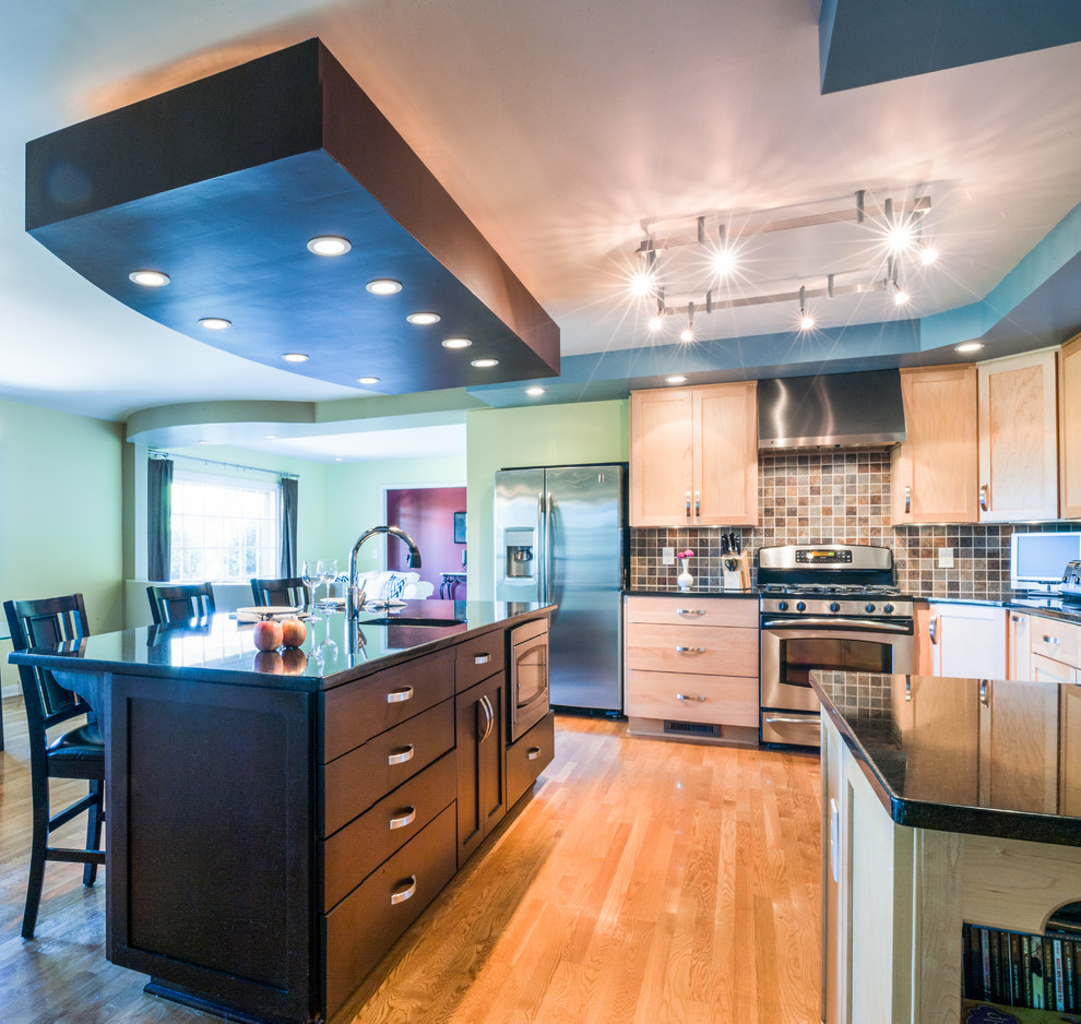 Example of a large eclectic u-shaped light wood floor kitchen design in Nashville with flat-panel cabinets, brown cabinets, granite countertops, multicolored backsplash, a drop-in sink and stainless steel appliances