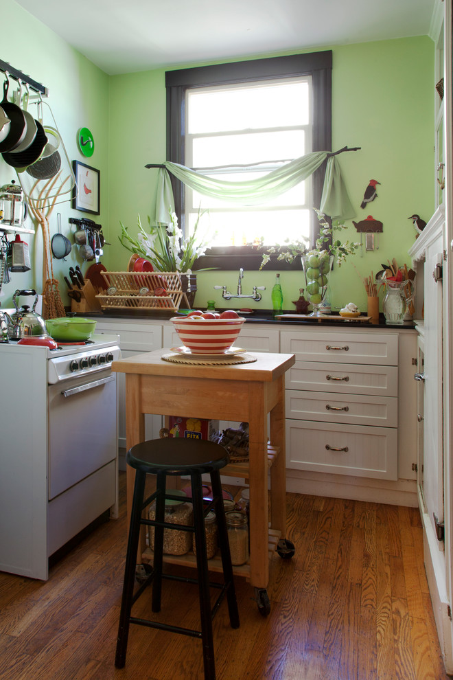 Kitchen - small eclectic u-shaped medium tone wood floor kitchen idea in San Francisco with recessed-panel cabinets, white cabinets, white appliances and an island