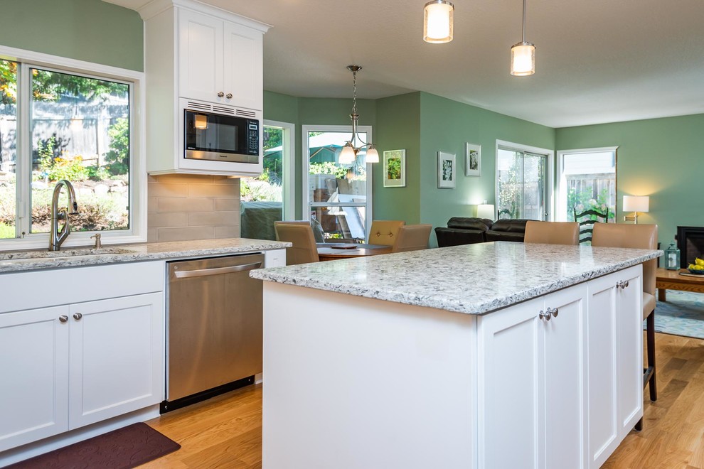 Example of a mid-sized classic l-shaped brown floor and vinyl floor eat-in kitchen design in Portland with an undermount sink, shaker cabinets, white cabinets, quartzite countertops, gray backsplash, stone tile backsplash, stainless steel appliances, an island and white countertops