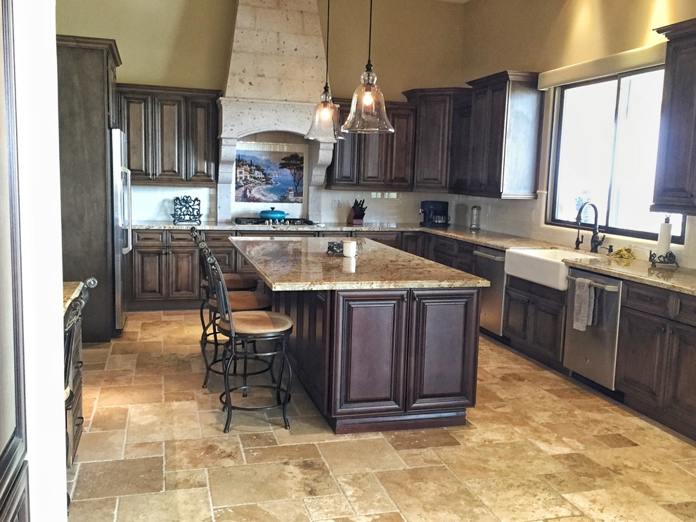 Exempel på ett stort klassiskt beige beige kök, med en rustik diskho, luckor med upphöjd panel, skåp i mörkt trä, granitbänkskiva, beige stänkskydd, stänkskydd i travertin, rostfria vitvaror, travertin golv, en köksö och beiget golv