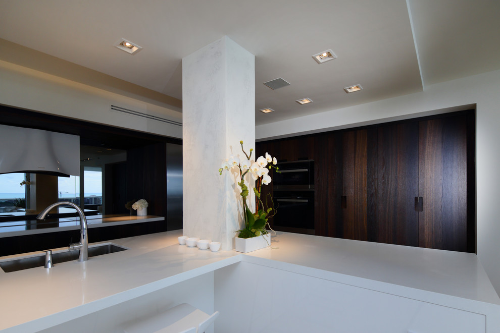 На фото: п-образная кухня-гостиная среднего размера в стиле модернизм с плоскими фасадами, белыми фасадами, столешницей из кварцита и полуостровом с