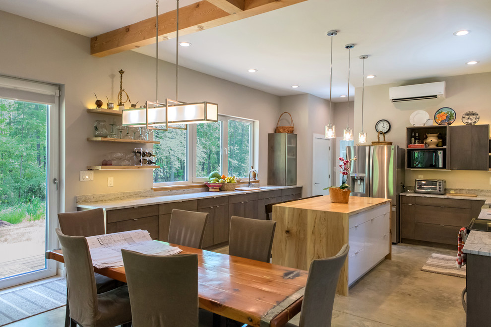 Immagine di una cucina moderna di medie dimensioni con lavello stile country, ante lisce, ante grigie, top in granito, paraspruzzi grigio, elettrodomestici in acciaio inossidabile e pavimento in cemento