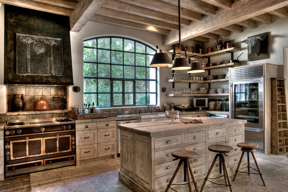 Diseño de cocina mediterránea con armarios estilo shaker, puertas de armario con efecto envejecido, encimera de madera, electrodomésticos de acero inoxidable y una isla
