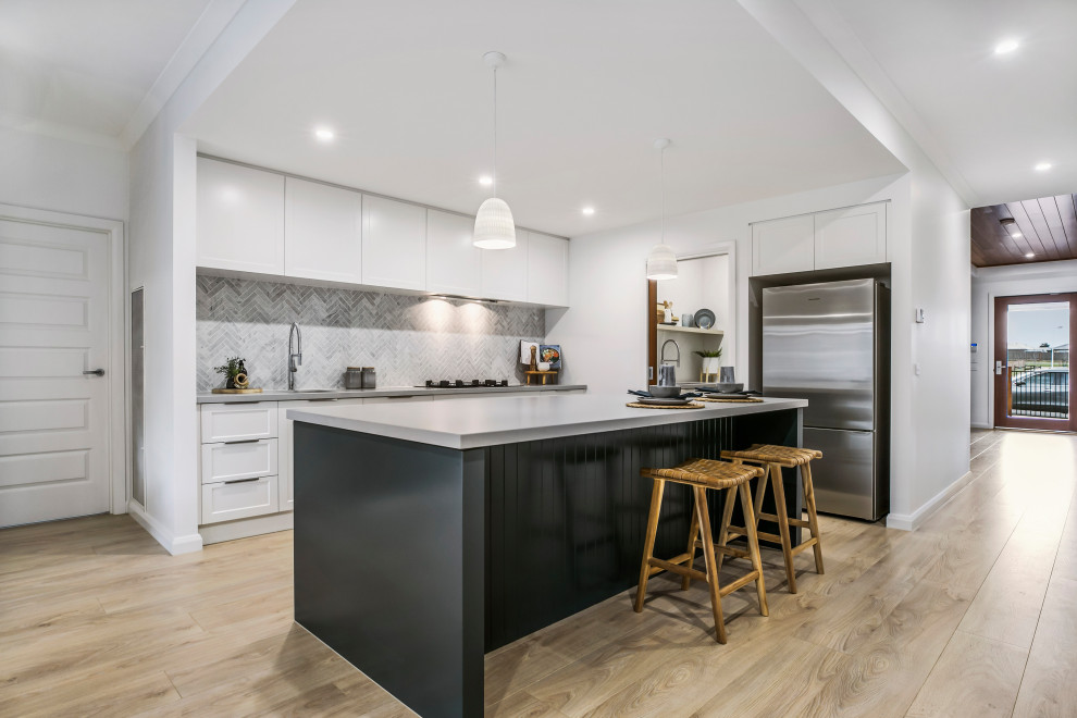 Foto di una cucina design di medie dimensioni con lavello sottopiano, ante bianche, paraspruzzi in marmo, elettrodomestici in acciaio inossidabile e top grigio