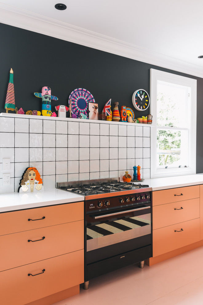 Moderne Küche mit Unterbauwaschbecken, Laminat-Arbeitsplatte, Küchenrückwand in Weiß, Rückwand aus Keramikfliesen, schwarzen Elektrogeräten, gebeiztem Holzboden, Kücheninsel, rosa Boden und oranger Arbeitsplatte in Sonstige