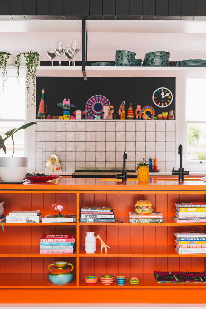 Foto på ett funkis orange kök, med en undermonterad diskho, laminatbänkskiva, vitt stänkskydd, stänkskydd i keramik, svarta vitvaror, målat trägolv, en köksö och rosa golv