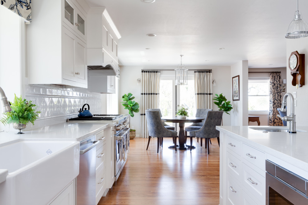 サクラメントにある高級な中くらいなトラディショナルスタイルのおしゃれなキッチン (エプロンフロントシンク、インセット扉のキャビネット、白いキャビネット、クオーツストーンカウンター、白いキッチンパネル、セラミックタイルのキッチンパネル、シルバーの調理設備、無垢フローリング、黄色い床、白いキッチンカウンター) の写真