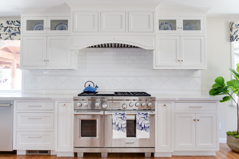 Bild på ett mellanstort vintage vit linjärt vitt kök och matrum, med en dubbel diskho, luckor med profilerade fronter, vita skåp, bänkskiva i kvarts, vitt stänkskydd, stänkskydd i keramik, rostfria vitvaror, mellanmörkt trägolv, en köksö och gult golv