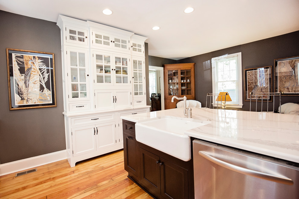 Bild på ett mellanstort funkis kök, med en rustik diskho, skåp i shakerstil, vita skåp, bänkskiva i kvarts, vitt stänkskydd, stänkskydd i keramik, rostfria vitvaror, mellanmörkt trägolv, en köksö och brunt golv