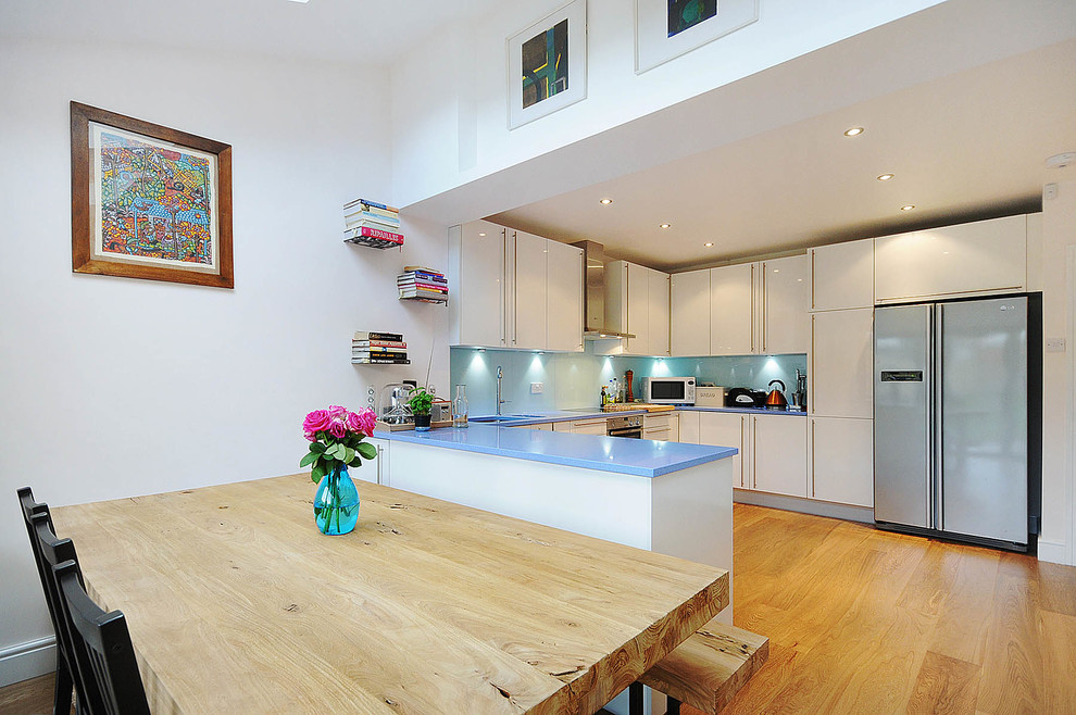 ロンドンにある広いモダンスタイルのおしゃれなキッチン (シングルシンク、オープンシェルフ、青いキャビネット、珪岩カウンター、青いキッチンパネル、ガラスタイルのキッチンパネル、カラー調理設備、スレートの床) の写真