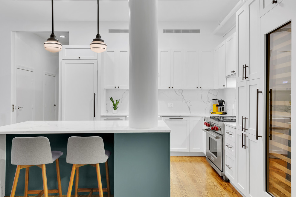Transitional l-shaped medium tone wood floor kitchen photo in New York with shaker cabinets, white cabinets, quartz countertops, white backsplash, white countertops, paneled appliances and an island