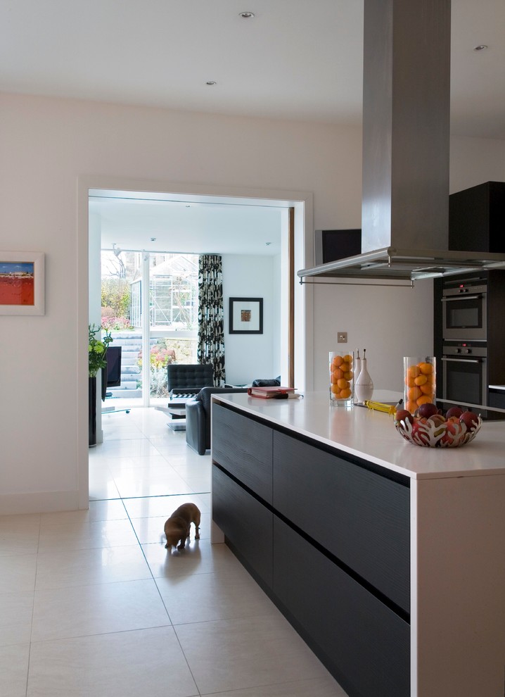 Bild på ett mellanstort funkis linjärt kök och matrum, med släta luckor, skåp i mörkt trä, bänkskiva i kvarts, rostfria vitvaror, klinkergolv i porslin och en köksö
