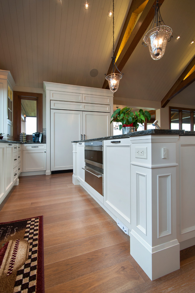Inspiration for a timeless u-shaped eat-in kitchen remodel in Vancouver with raised-panel cabinets and white cabinets