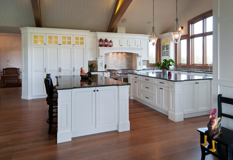 На фото: п-образная кухня в классическом стиле с обеденным столом, фасадами с выступающей филенкой и белыми фасадами