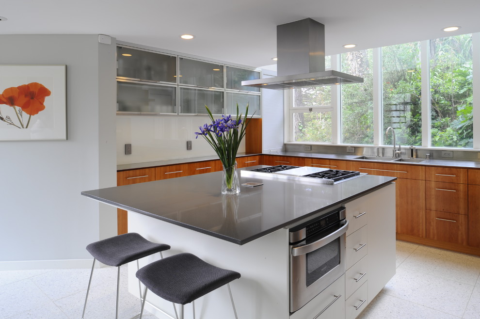 Design ideas for a contemporary u-shaped kitchen/diner in San Francisco with a double-bowl sink, flat-panel cabinets, medium wood cabinets, grey splashback, metal splashback, stainless steel appliances, porcelain flooring and an island.