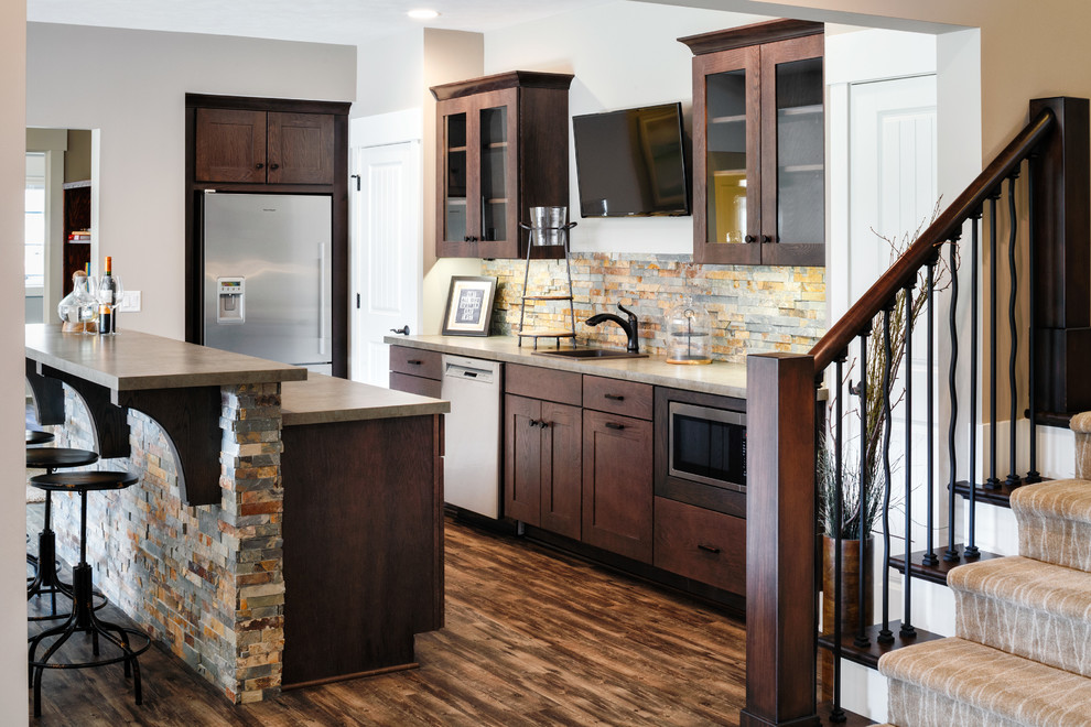 Medium sized rustic single-wall open plan kitchen in Grand Rapids with a built-in sink, recessed-panel cabinets, dark wood cabinets, granite worktops, multi-coloured splashback, mosaic tiled splashback, stainless steel appliances, medium hardwood flooring and an island.
