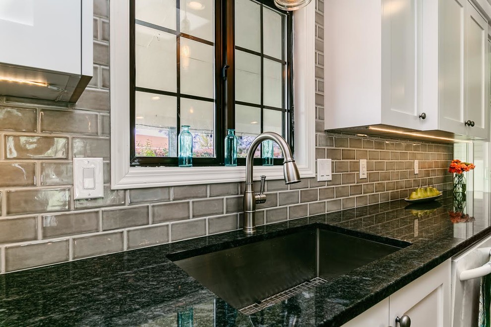 Kitchen - mid-sized transitional l-shaped dark wood floor and brown floor kitchen idea in Boise with an undermount sink, shaker cabinets, white cabinets, granite countertops, gray backsplash, ceramic backsplash, stainless steel appliances, an island and black countertops