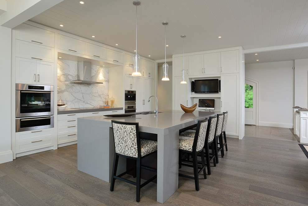 This is an example of a contemporary l-shaped open plan kitchen in Toronto with shaker cabinets and white cabinets.