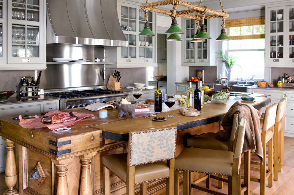 На фото: кухня в морском стиле с с полувстраиваемой мойкой (с передним бортиком), стеклянными фасадами, серыми фасадами, деревянной столешницей и техникой из нержавеющей стали