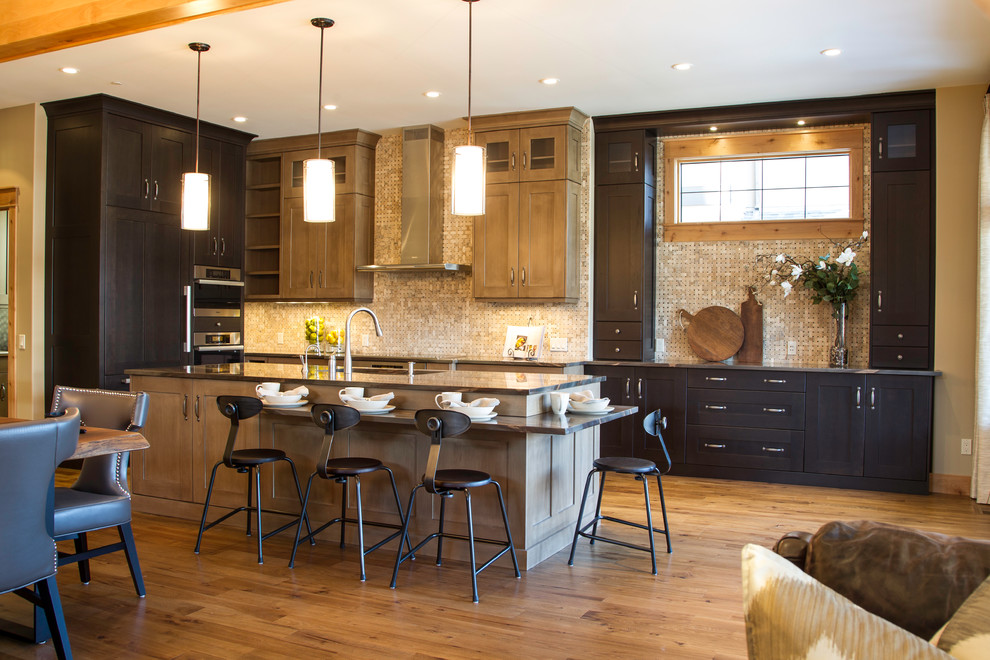 Elegant medium tone wood floor open concept kitchen photo in Calgary with shaker cabinets, dark wood cabinets, beige backsplash and paneled appliances