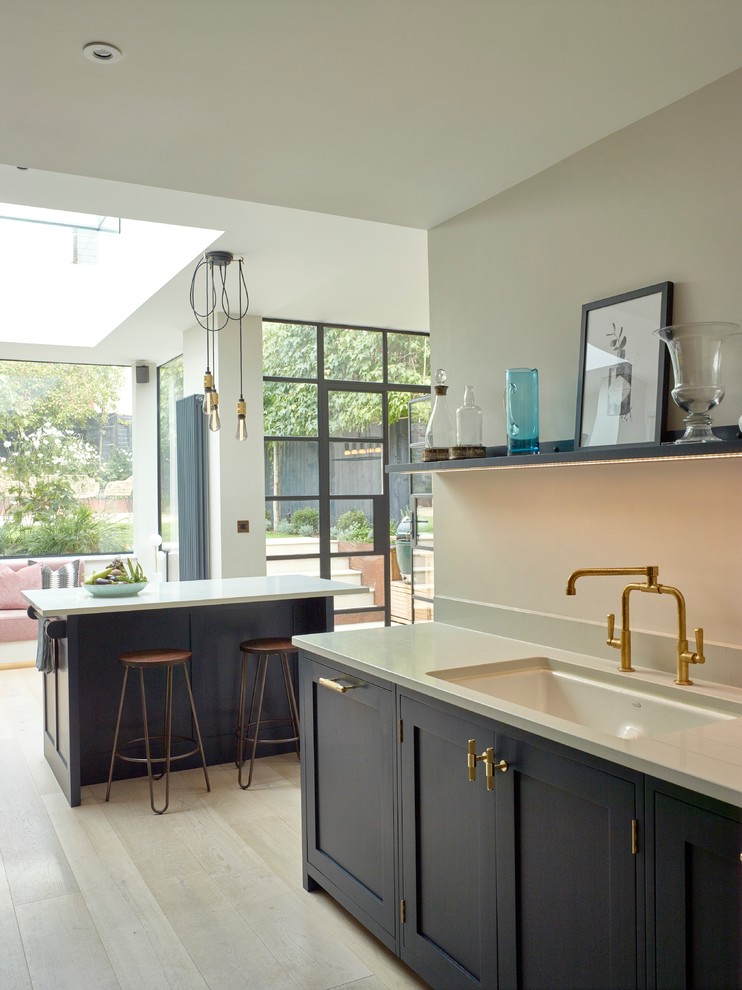Foto di una cucina contemporanea di medie dimensioni con lavello a doppia vasca, ante in stile shaker, ante blu, top in superficie solida, elettrodomestici in acciaio inossidabile, parquet chiaro e top bianco