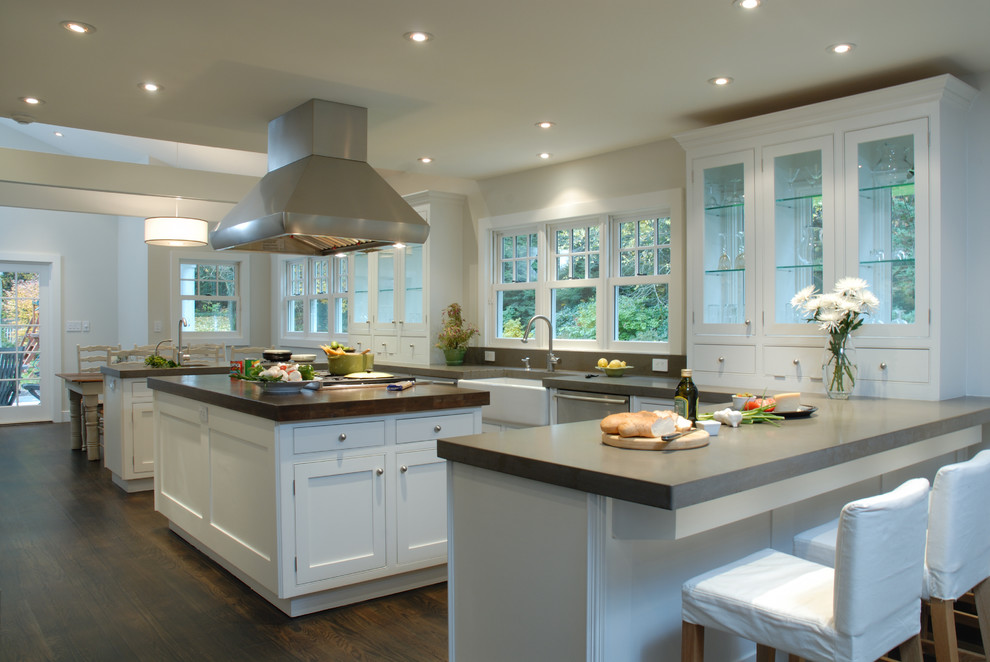 This is an example of a contemporary u-shaped kitchen/diner in New York with a belfast sink, glass-front cabinets, white cabinets, grey splashback and stainless steel appliances.