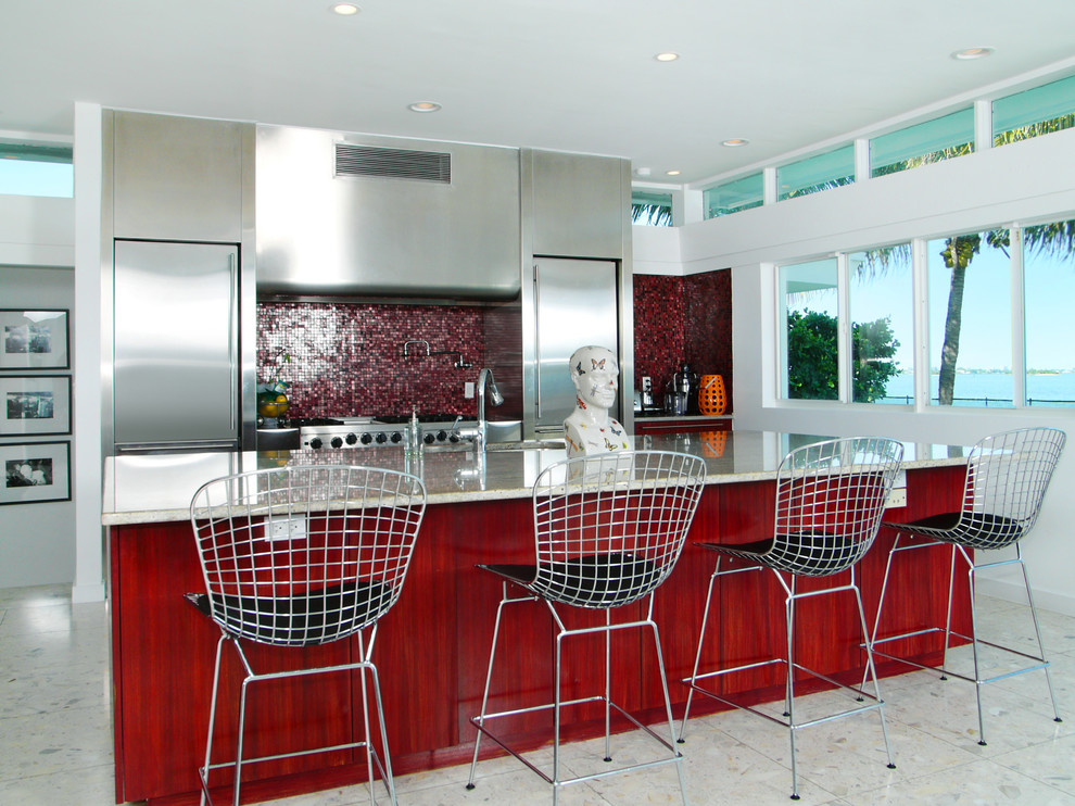 Idée de décoration pour une cuisine parallèle design en inox avec un placard à porte plane, une crédence rouge, une crédence en mosaïque et un électroménager en acier inoxydable.