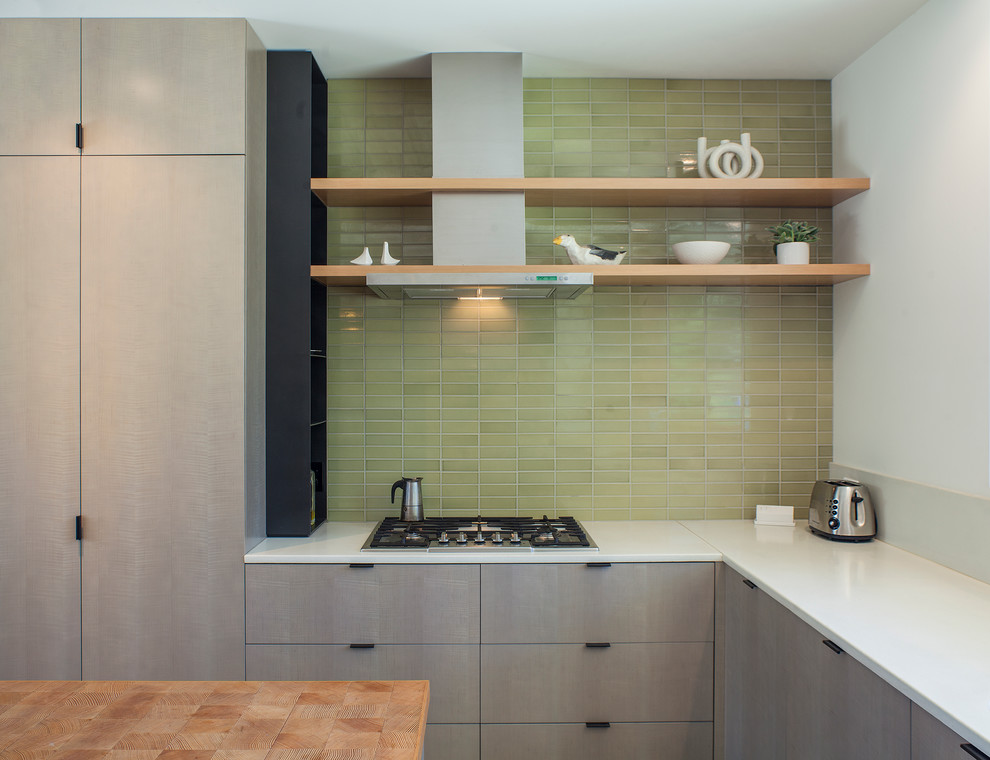 Cette photo montre une cuisine tendance de taille moyenne avec un placard à porte plane, des portes de placard grises, une crédence verte, une crédence en céramique et îlot.