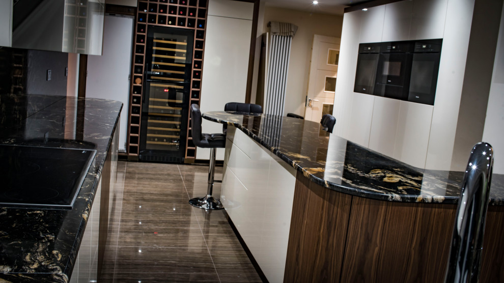 Photo of an expansive contemporary kitchen in Hampshire with glass-front cabinets, dark wood cabinets, marble worktops, stainless steel appliances and multiple islands.