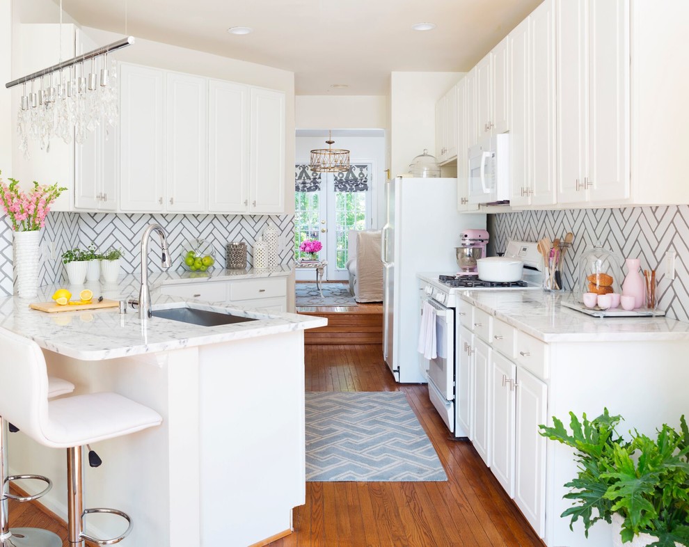 Exempel på ett klassiskt kök, med en undermonterad diskho, luckor med upphöjd panel, vita skåp, vitt stänkskydd, stänkskydd i tunnelbanekakel, vita vitvaror, mellanmörkt trägolv och en halv köksö