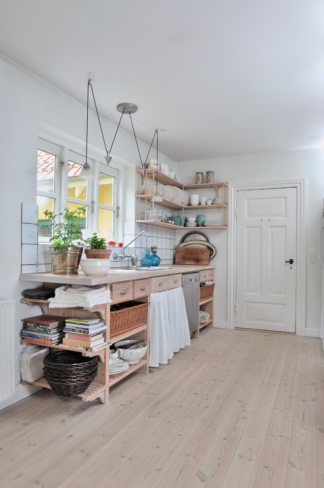 Inredning av ett nordiskt mellanstort kök, med en nedsänkt diskho, öppna hyllor, skåp i ljust trä, vitt stänkskydd, träbänkskiva, målat trägolv och en köksö
