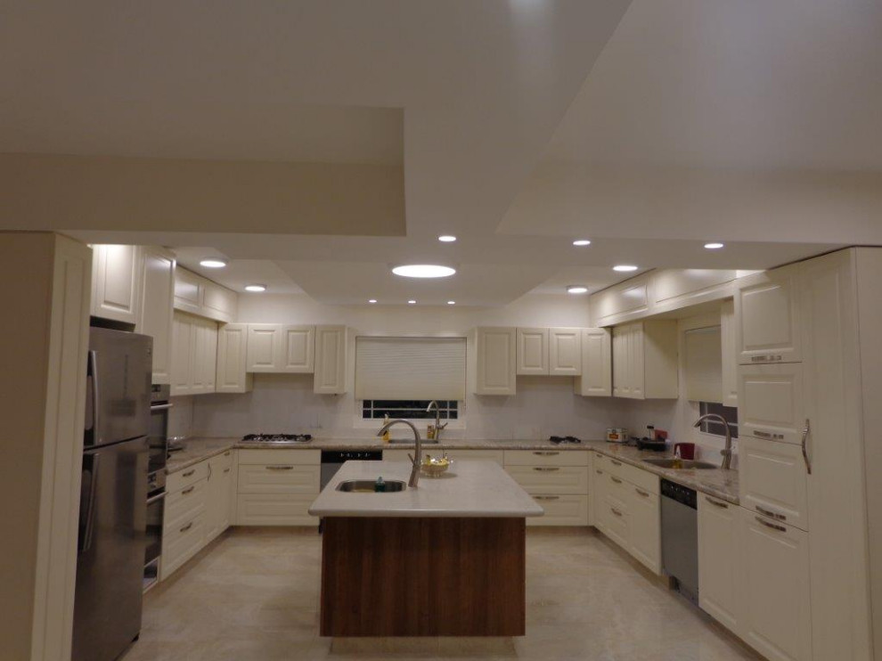 Example of a large urban u-shaped ceramic tile and beige floor kitchen pantry design in Other with an integrated sink, shaker cabinets, beige cabinets, granite countertops, white backsplash, glass sheet backsplash, stainless steel appliances, an island and brown countertops