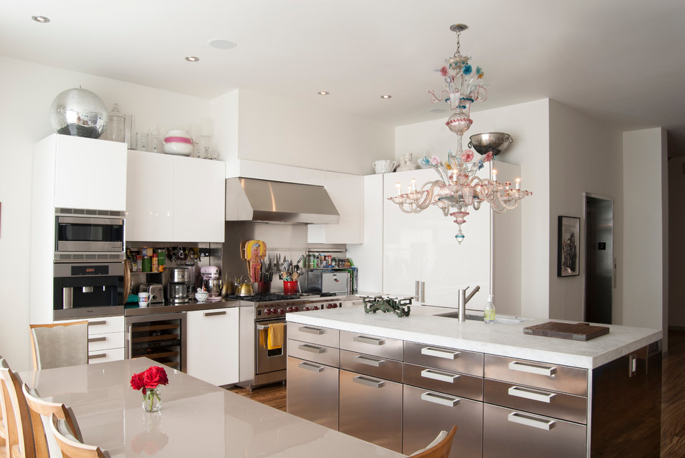 Large trendy medium tone wood floor eat-in kitchen photo in New York with an undermount sink, flat-panel cabinets, white cabinets, metallic backsplash, stainless steel appliances and an island