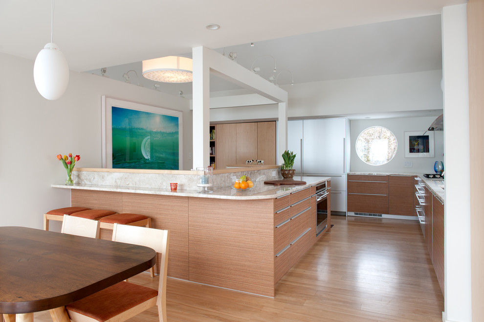 Foto på ett funkis kök och matrum, med släta luckor, marmorbänkskiva, rostfria vitvaror, ljust trägolv och flera köksöar