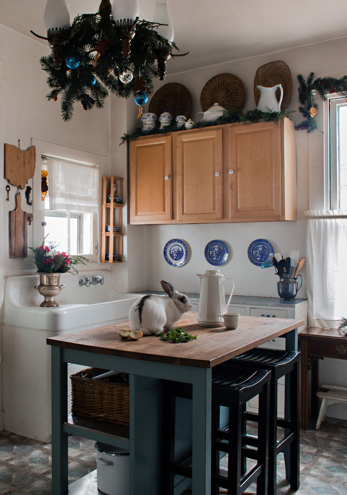 Foto di una cucina country con lavello stile country, ante con bugna sagomata, ante in legno scuro, top in legno, paraspruzzi bianco, pavimento grigio e top marrone
