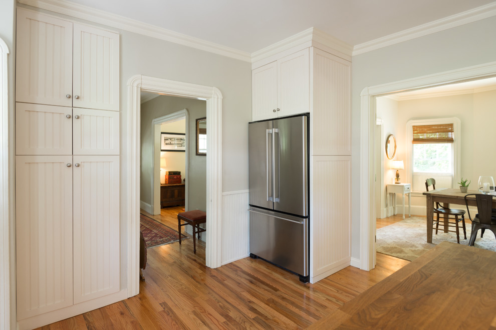 Ejemplo de cocina de estilo de casa de campo de tamaño medio con armarios estilo shaker, puertas de armario blancas, encimera de madera, una isla y suelo de madera clara