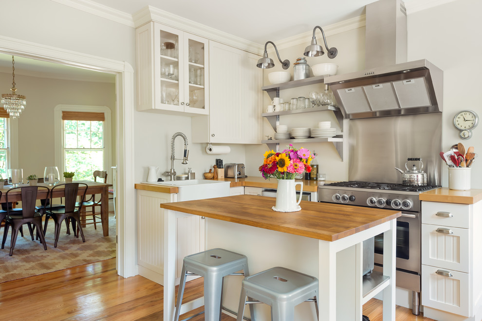 Foto på ett mellanstort lantligt l-kök, med skåp i shakerstil, vita skåp, träbänkskiva, en köksö, ljust trägolv, en rustik diskho och rostfria vitvaror