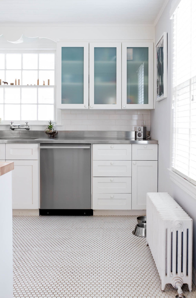 Modern inredning av ett kök, med bänkskiva i rostfritt stål, en integrerad diskho och vitt golv