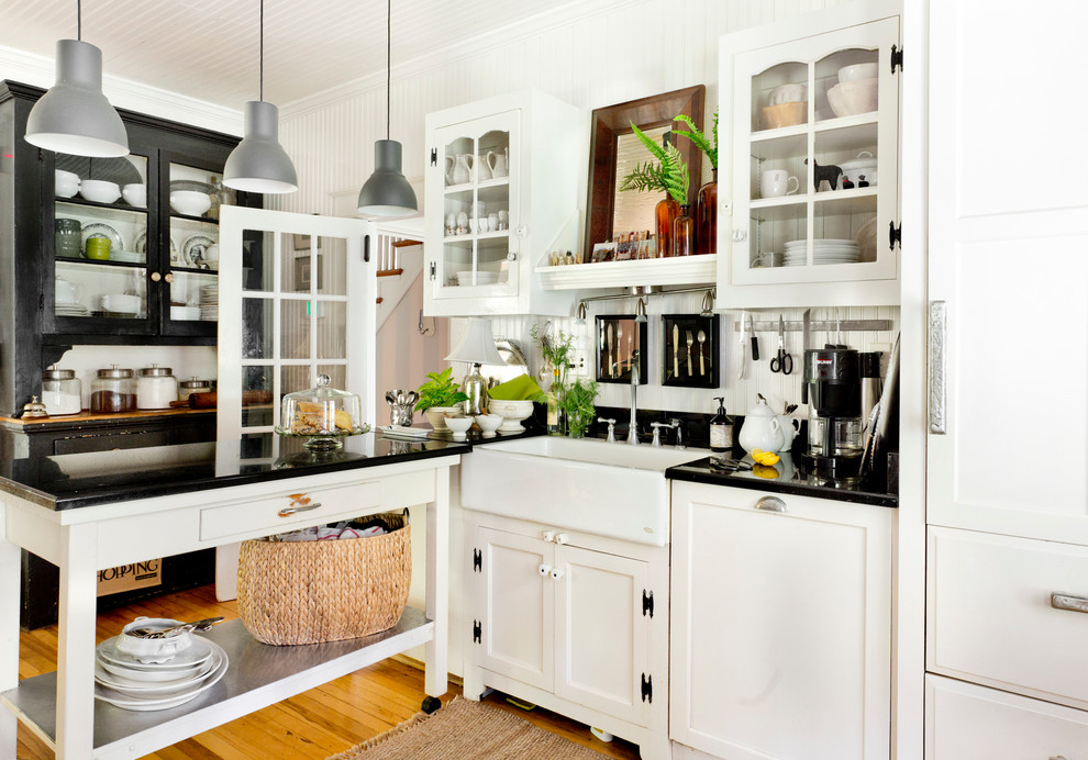 Klassische Küche in L-Form mit Landhausspüle, Schrankfronten mit vertiefter Füllung und braunem Holzboden in New York
