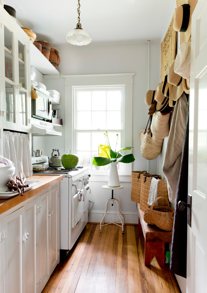 Cette photo montre une cuisine chic avec un plan de travail en bois, un électroménager blanc et un sol en bois brun.